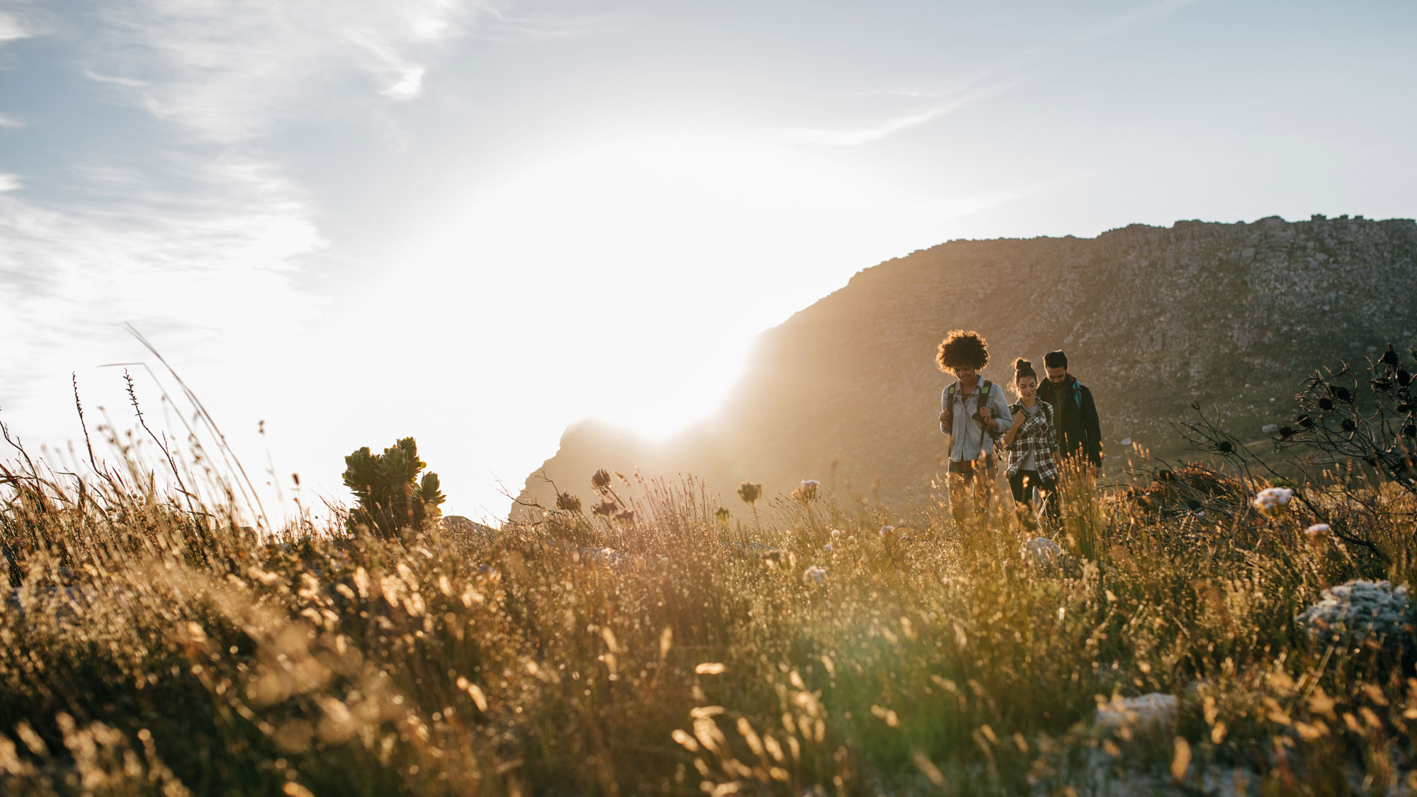 Three young people hiking at sunset.